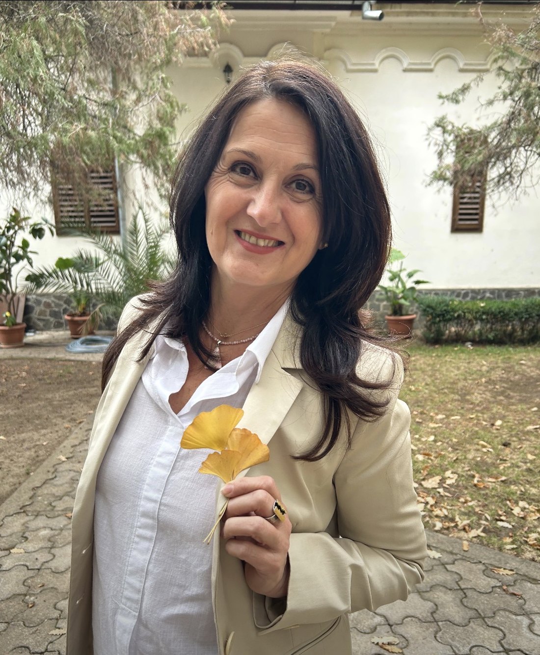 Gabi smiling outdoors, holding golden ginkgo leaves